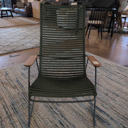 Green lounge chair on a patterned rug in a room with furniture and people in the background