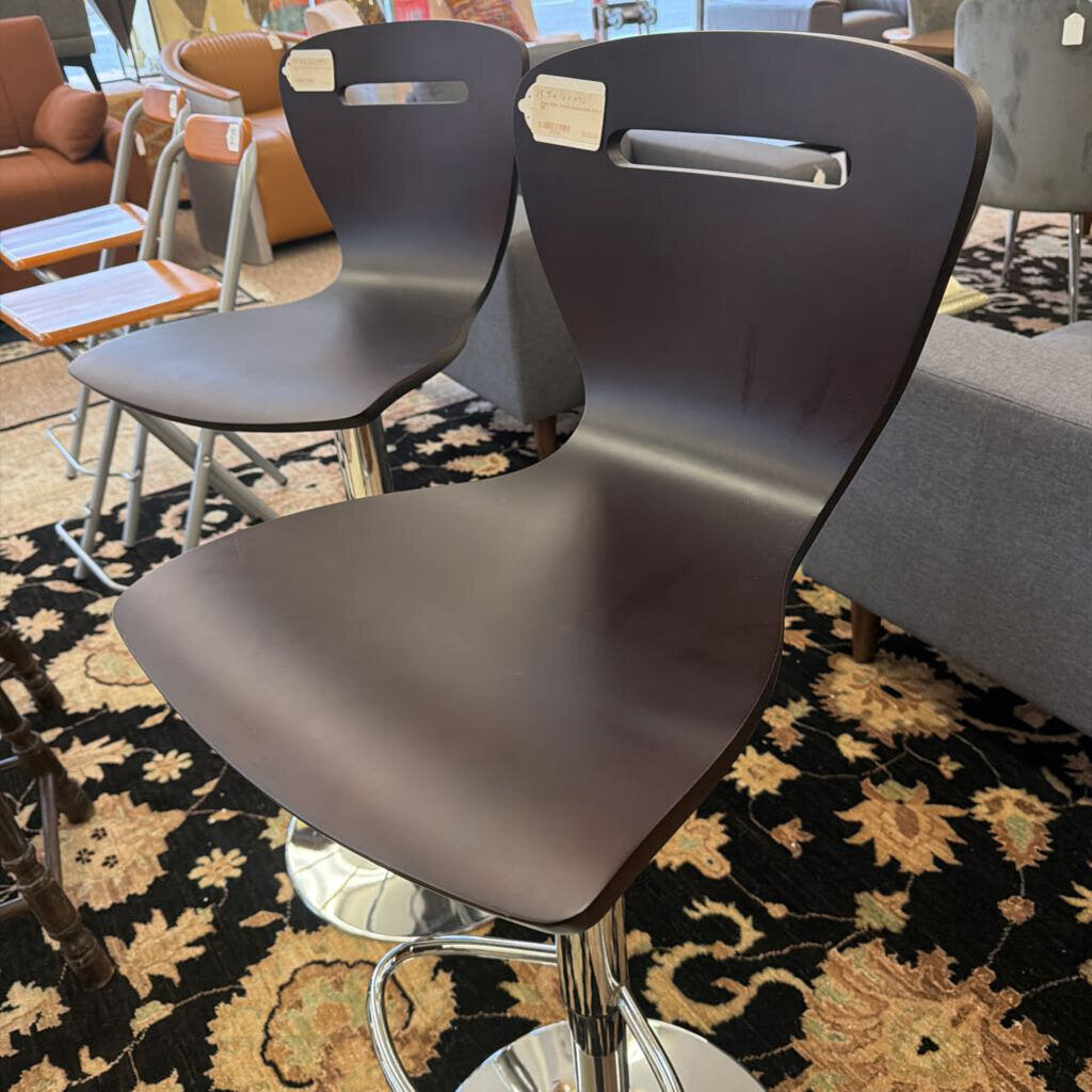 Two brown bar stools with metal legs on a patterned rug in a casual setting.