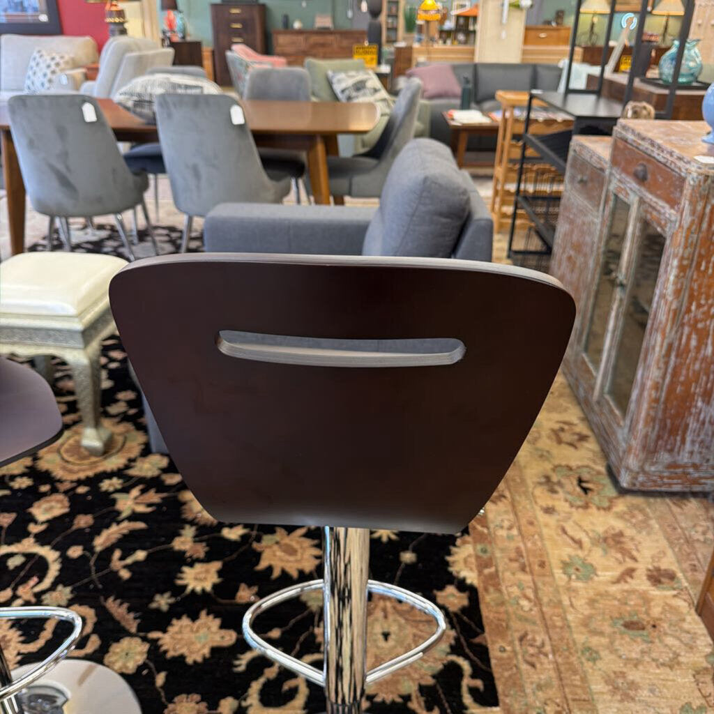 Bar stool with brown backrest and silver base in a furniture store setting