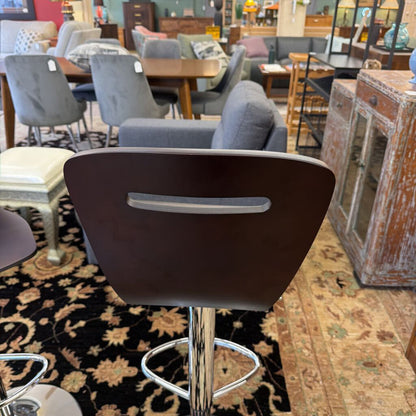 Bar stool with brown backrest and silver base in a furniture store setting