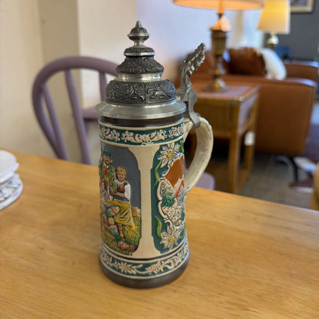 Decorative ceramic stein with intricate designs on a wooden table.