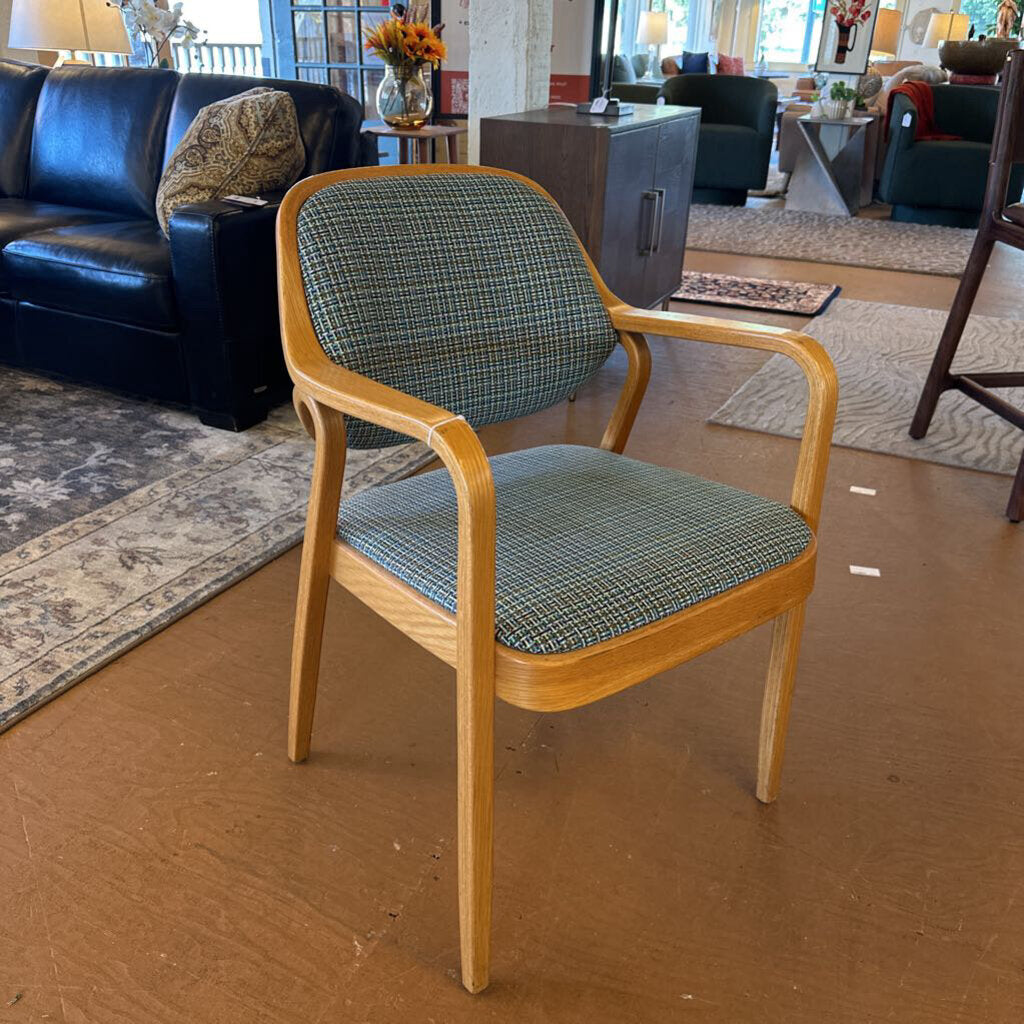 Chair with wooden frame and plaid cushion in a room with furniture and decor.