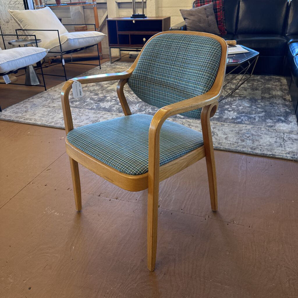 Chair with wooden frame and green checkered cushion in a room with furniture.