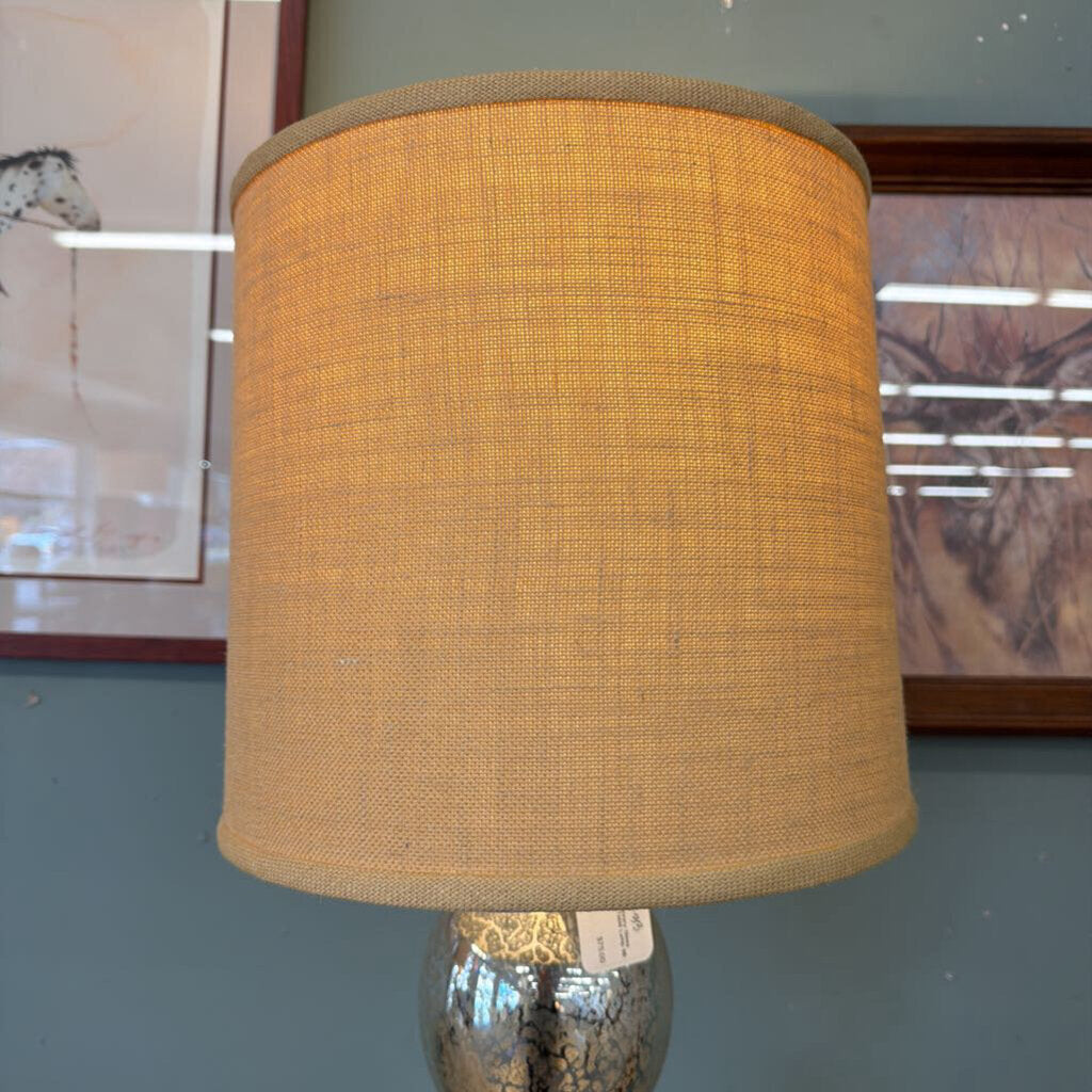 Textured beige lampshade on a metallic base against a neutral background