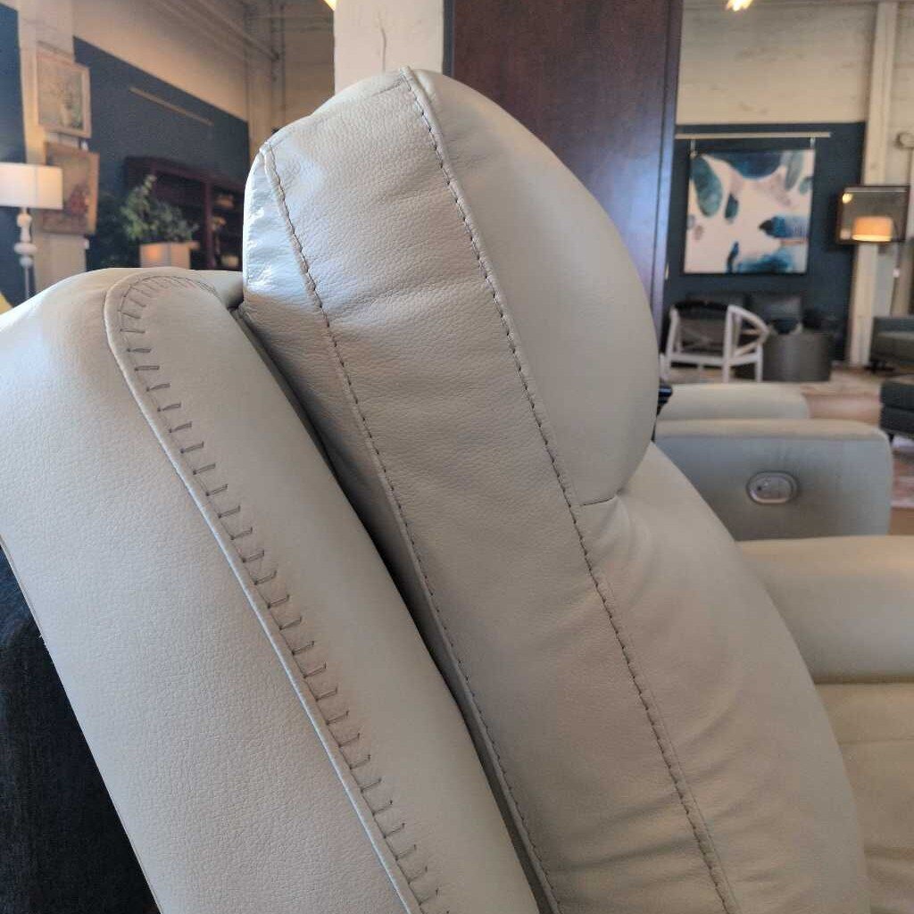 Close-up of a beige leather recliner chair with stitching details, blurred background