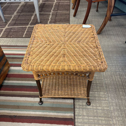 Wicker side table on a carpeted floor with a striped rug