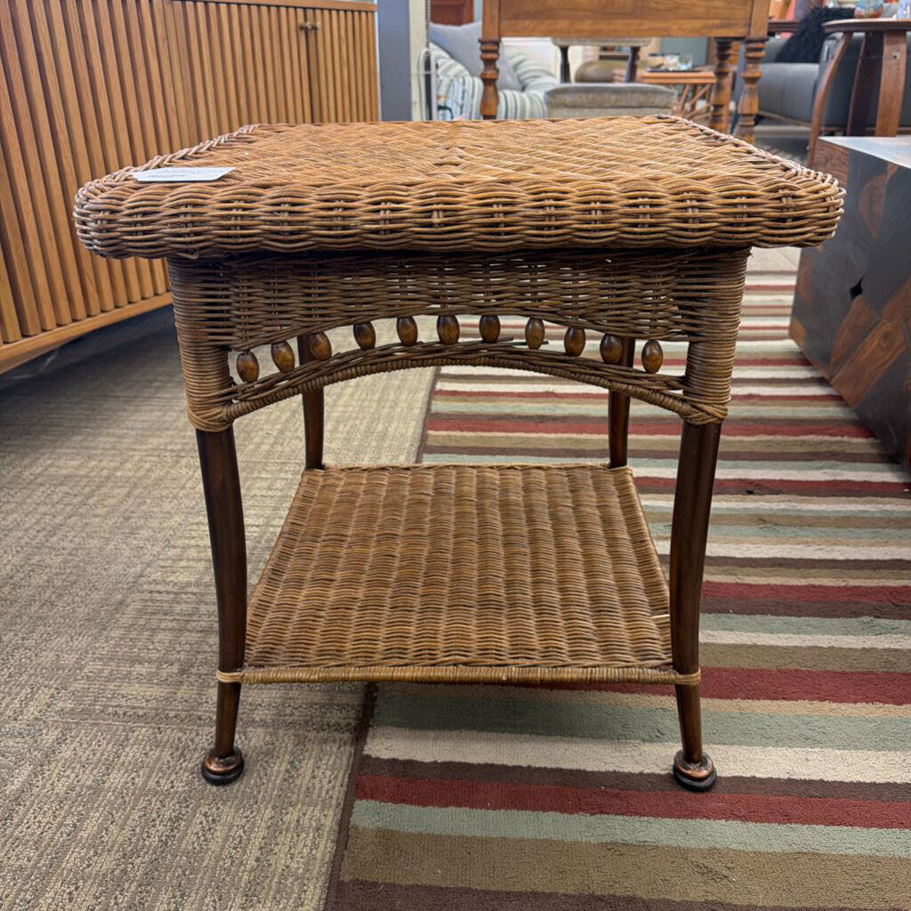 Wicker side table in a room with striped carpet