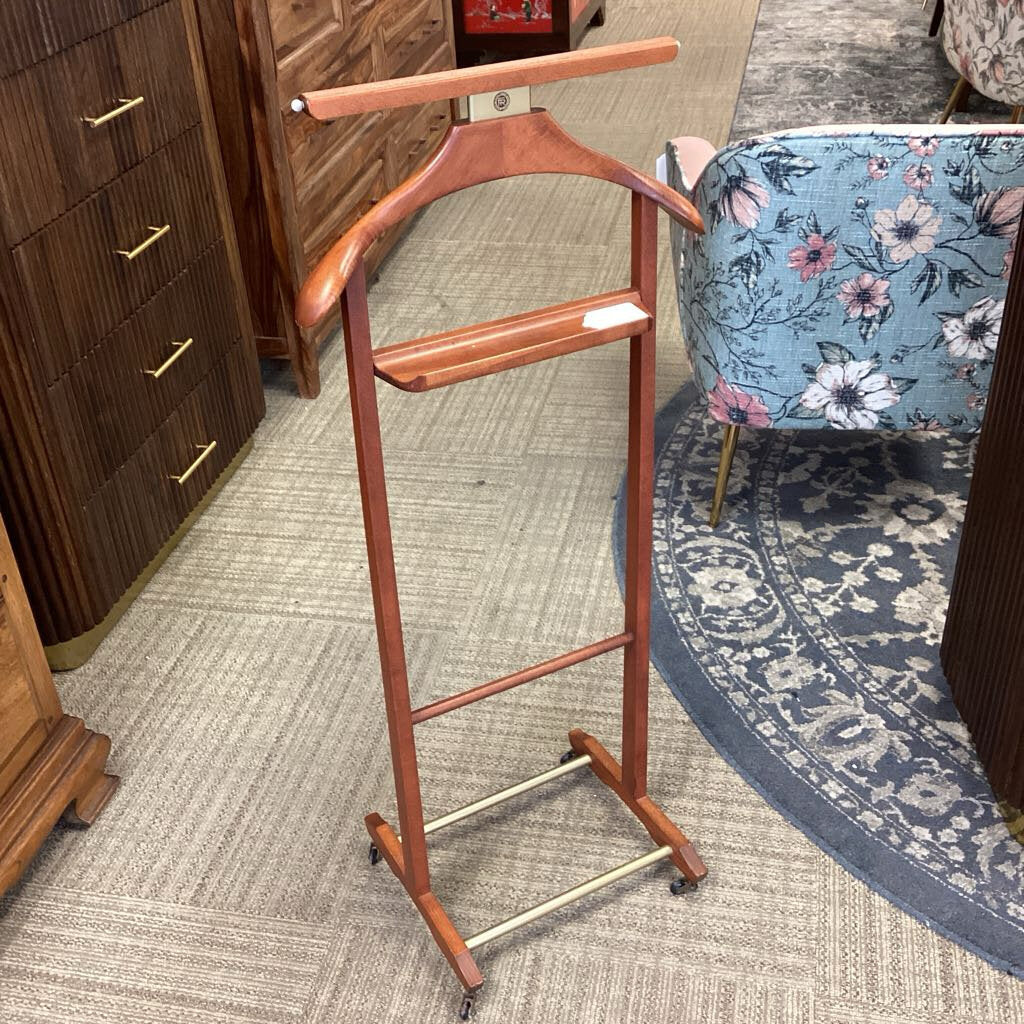Wooden coat stand on a carpeted floor with a floral chair in the background.