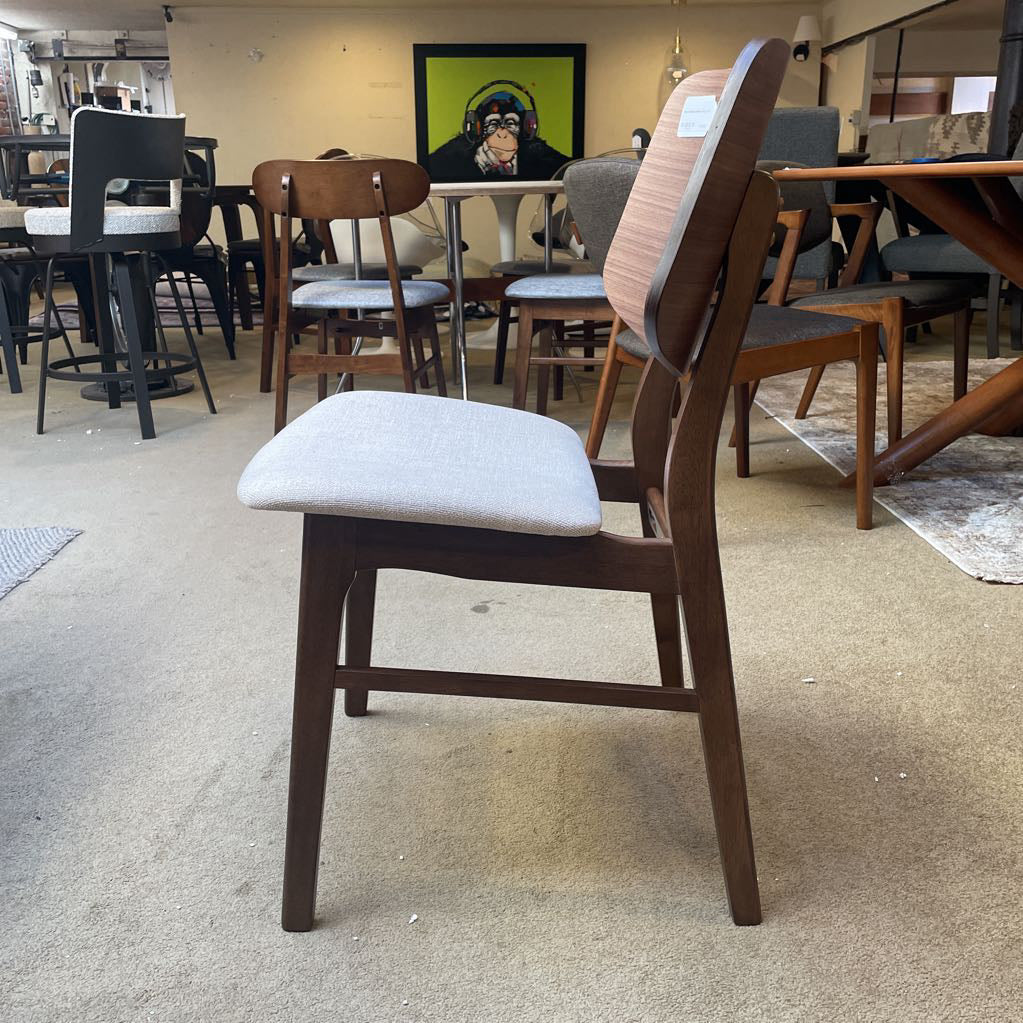 Wooden chair with a gray cushion on a carpeted floor in a furniture store.