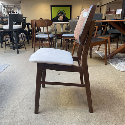 Wooden chair with a gray cushion on a carpeted floor in a furniture store.