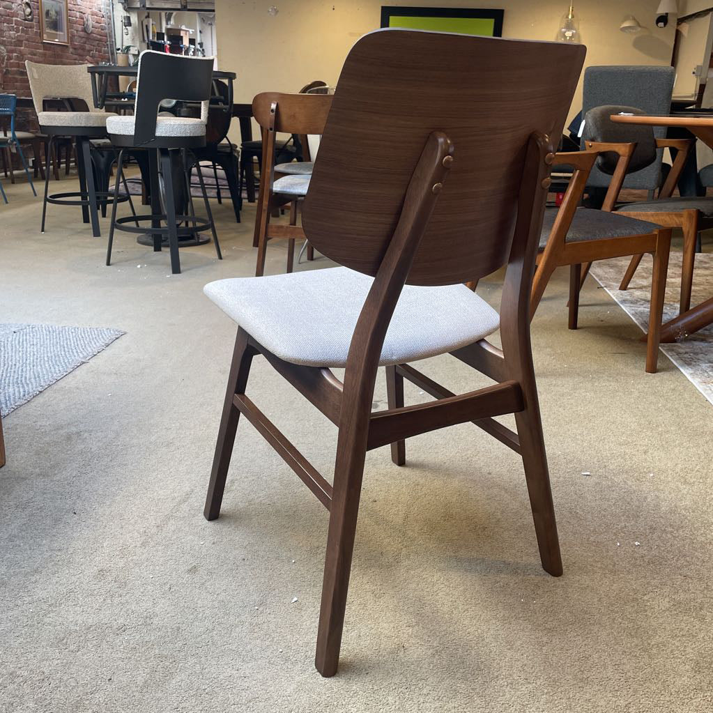 Wooden chair with a white cushion on a carpeted floor in a furniture store.