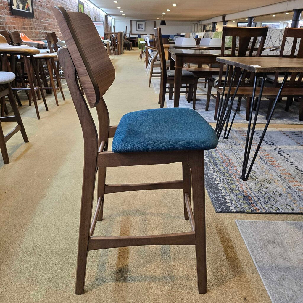 Wooden bar stool with a blue seat in a casual dining setting.