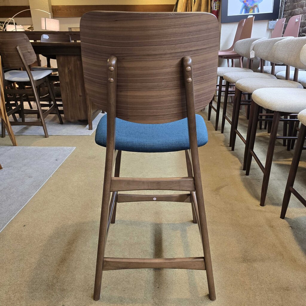 Wooden bar stool with a blue cushion in a showroom setting