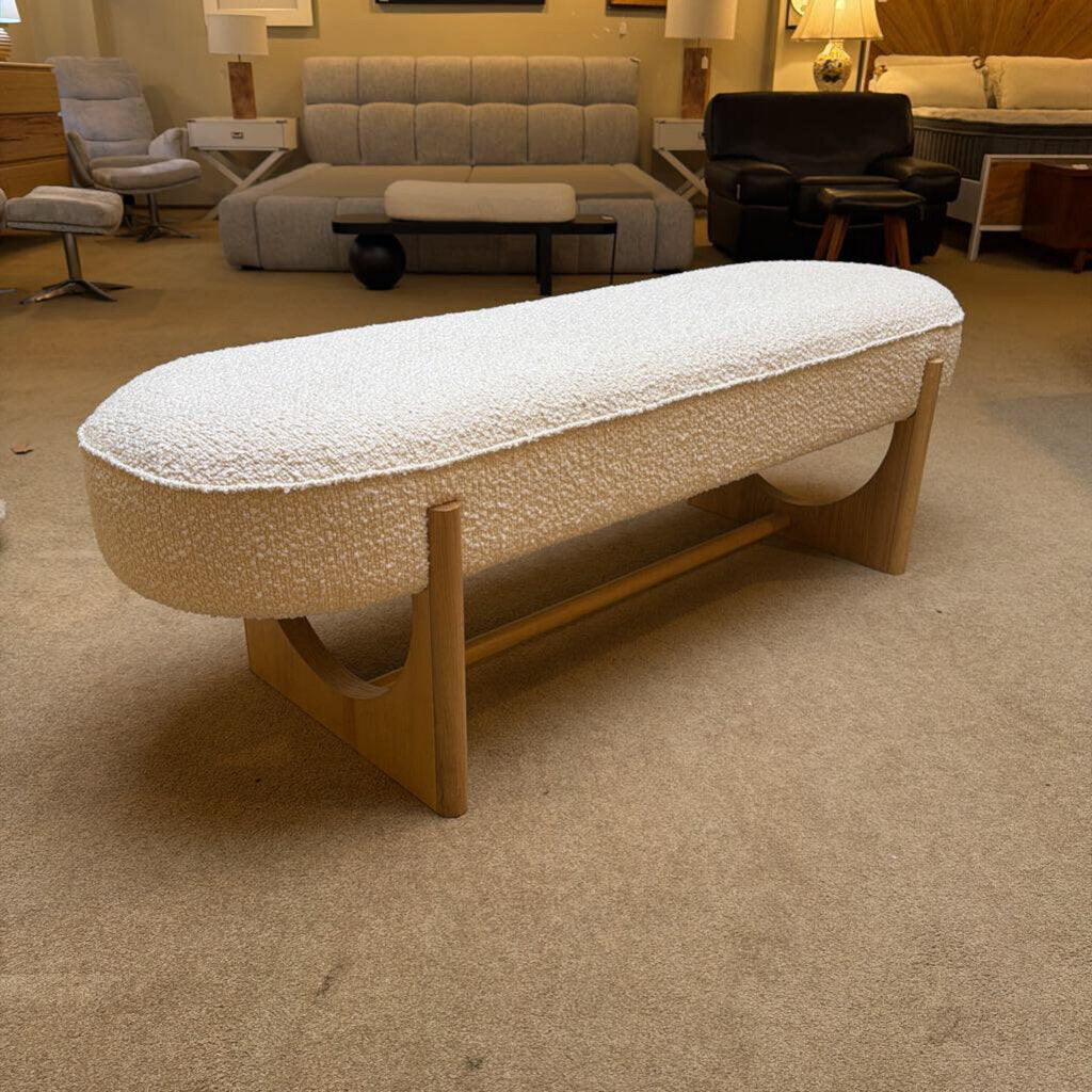 Beige textured ottoman with wooden legs in a room setting
