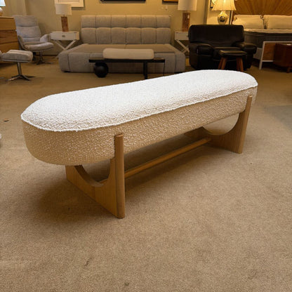 Beige textured ottoman with wooden legs in a room setting