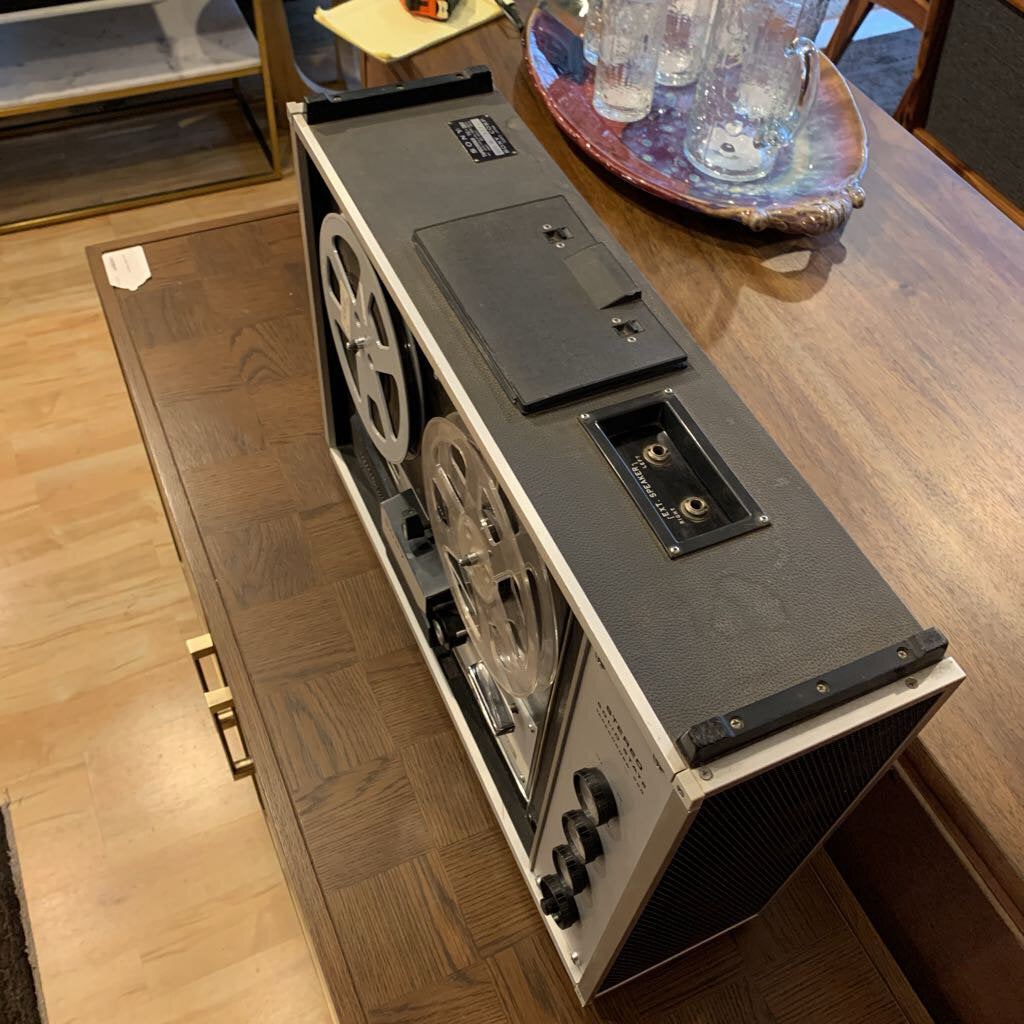 Vintage reel-to-reel tape recorder on a wooden floor