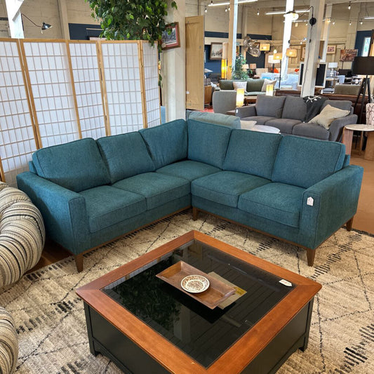 Blue sectional sofa in a showroom with a wooden coffee table and decorative items.