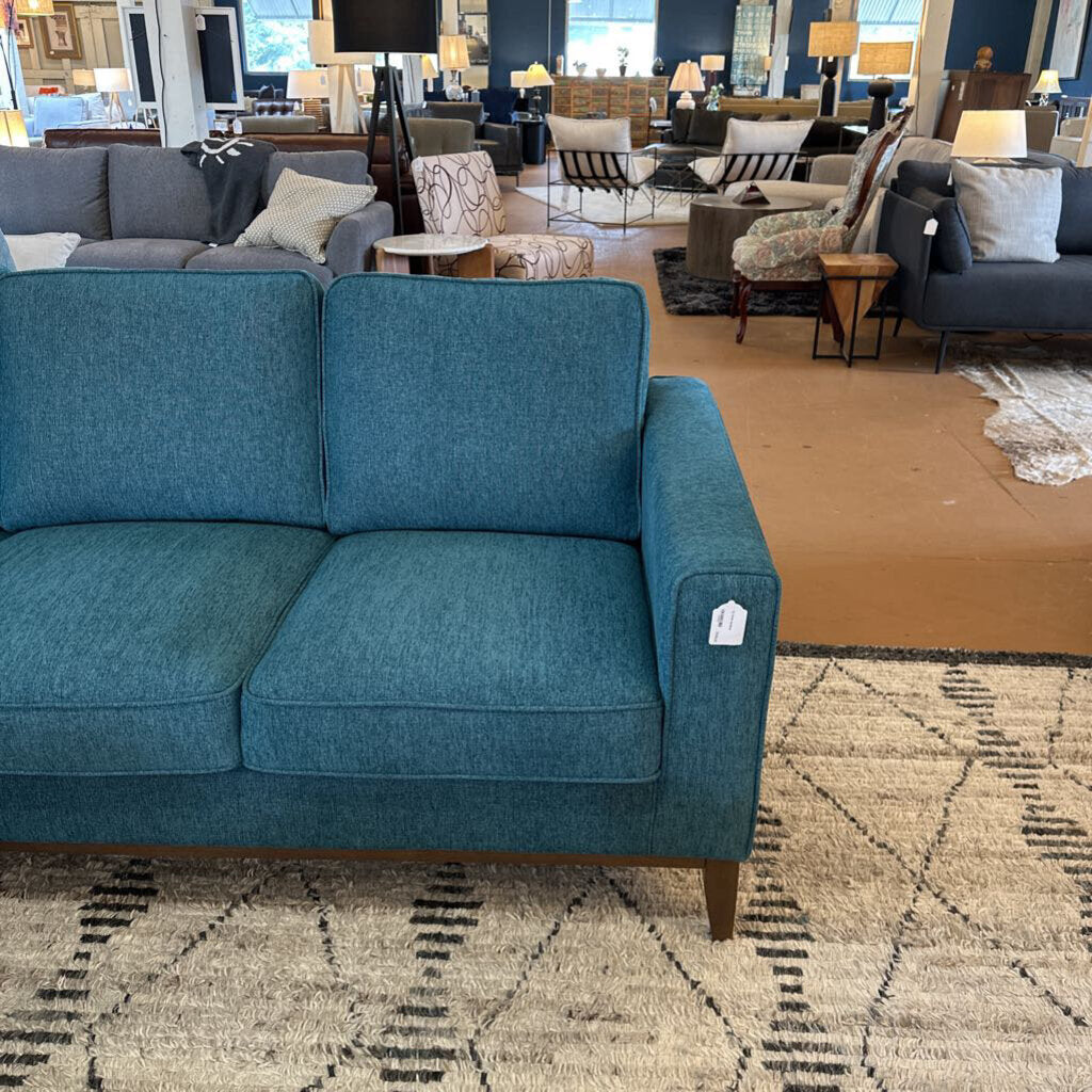 Blue sofa in a furniture store with other sofas and decor in the background.