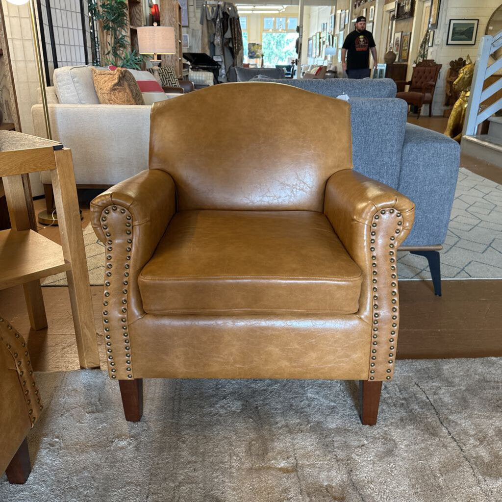 Brown leather armchair with nailhead trim in a furniture store setting
