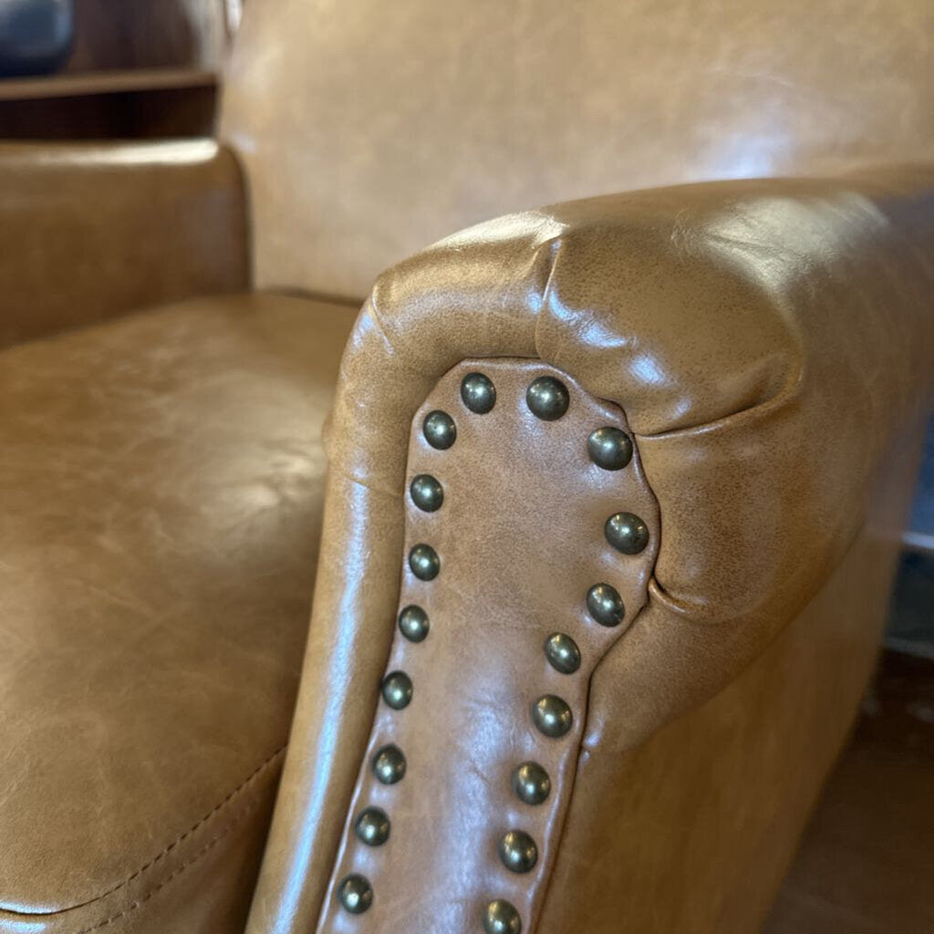 Close-up of a brown leather armchair with studded details.