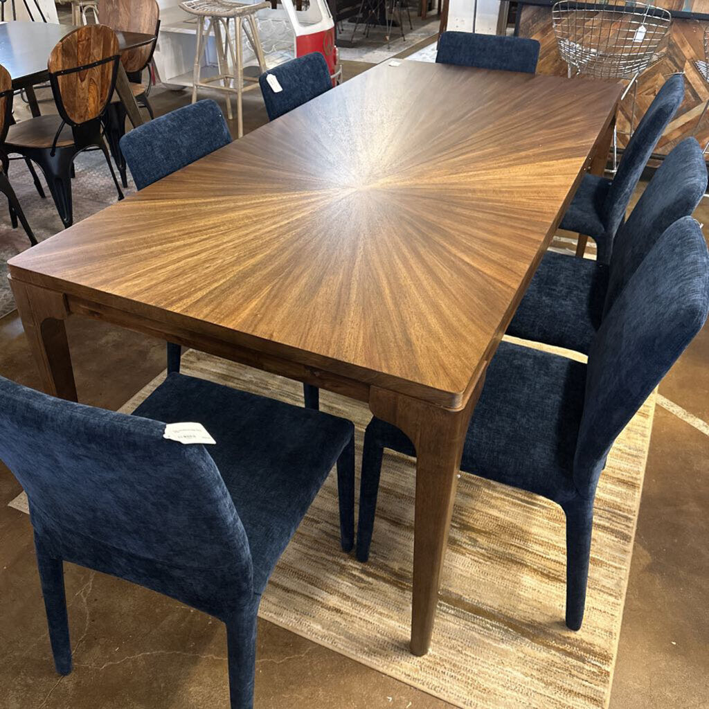 Wooden dining table with blue chairs in a showroom setting