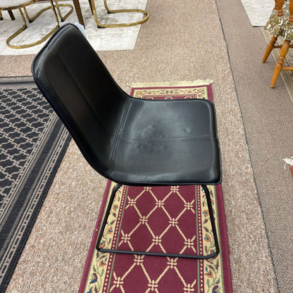 Black chair on a patterned rug with a carpeted floor in the background