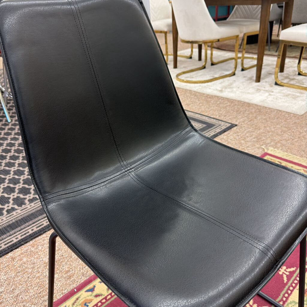 Black leather chair in a room with patterned rug and other chairs.