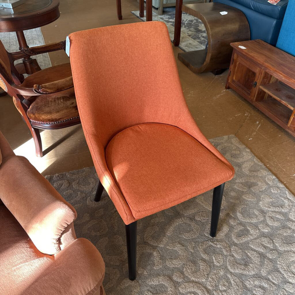 Orange chair with black legs in a room with furniture
