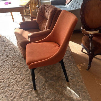 Orange chair in a room with a patterned rug and wooden furniture.