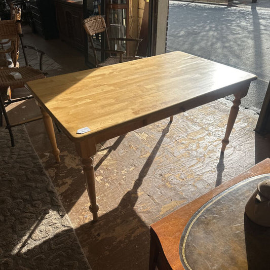 Wooden table on a stone patio with chairs in the background