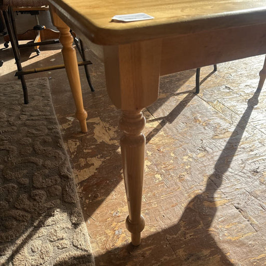 Wooden table with a single leg on a stone floor