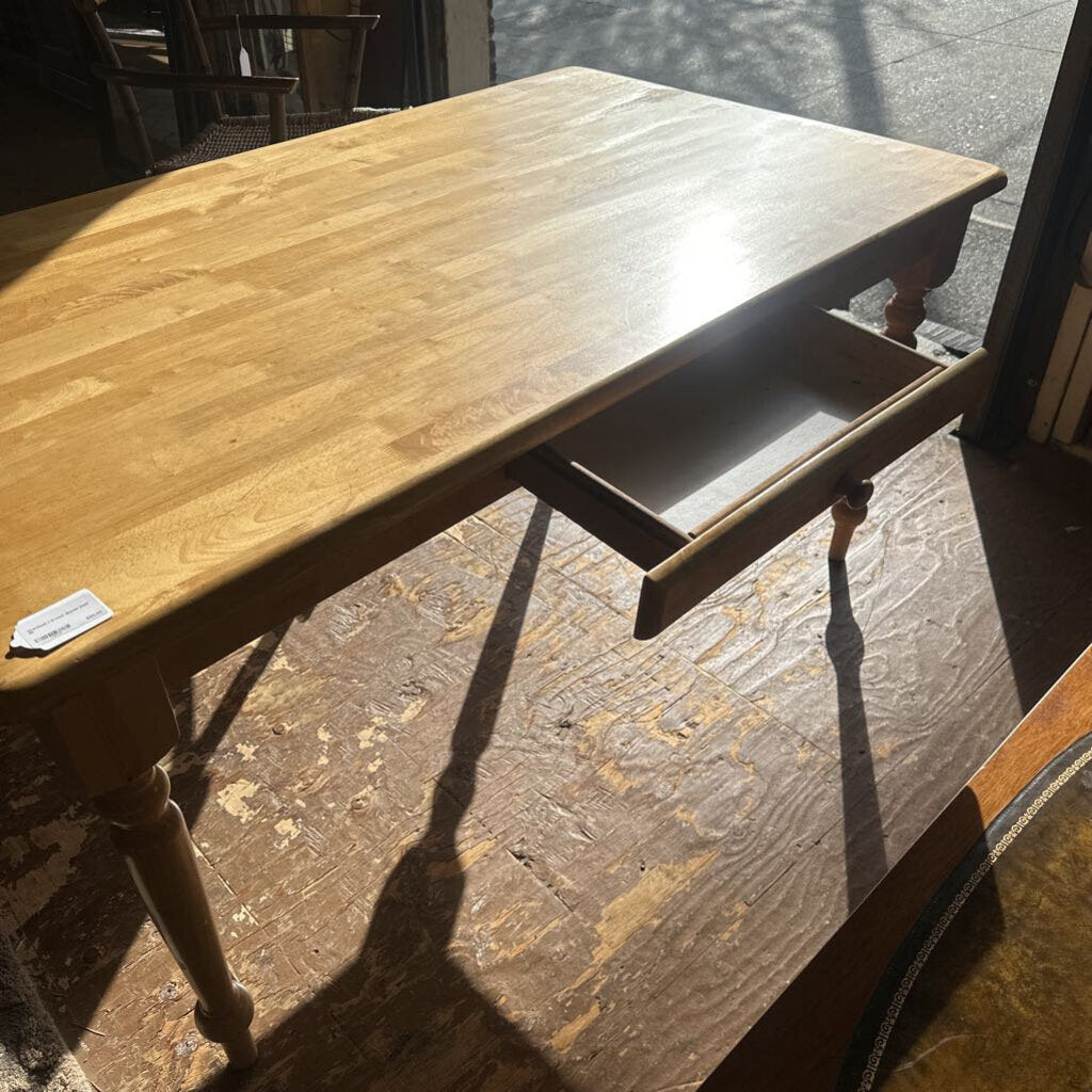 Wooden table with a drawer open on a stone floor