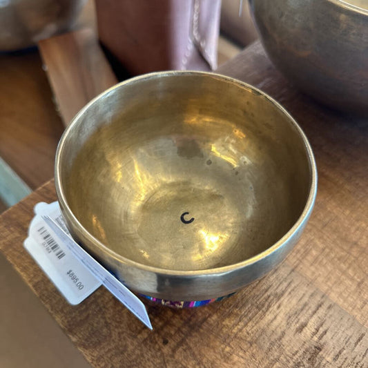 Gold singing bowl with a label on a wooden surface