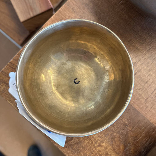 Brass singing bowl with a logo on a wooden surface