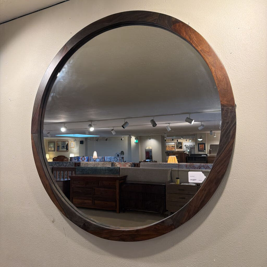 Round wooden-framed mirror on a wall