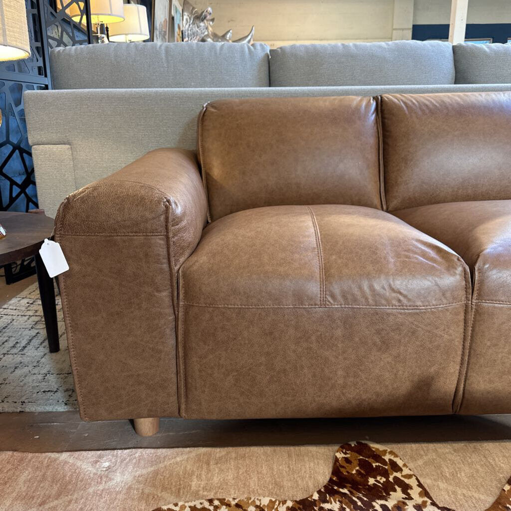 Brown leather sofa with a price tag in a store setting