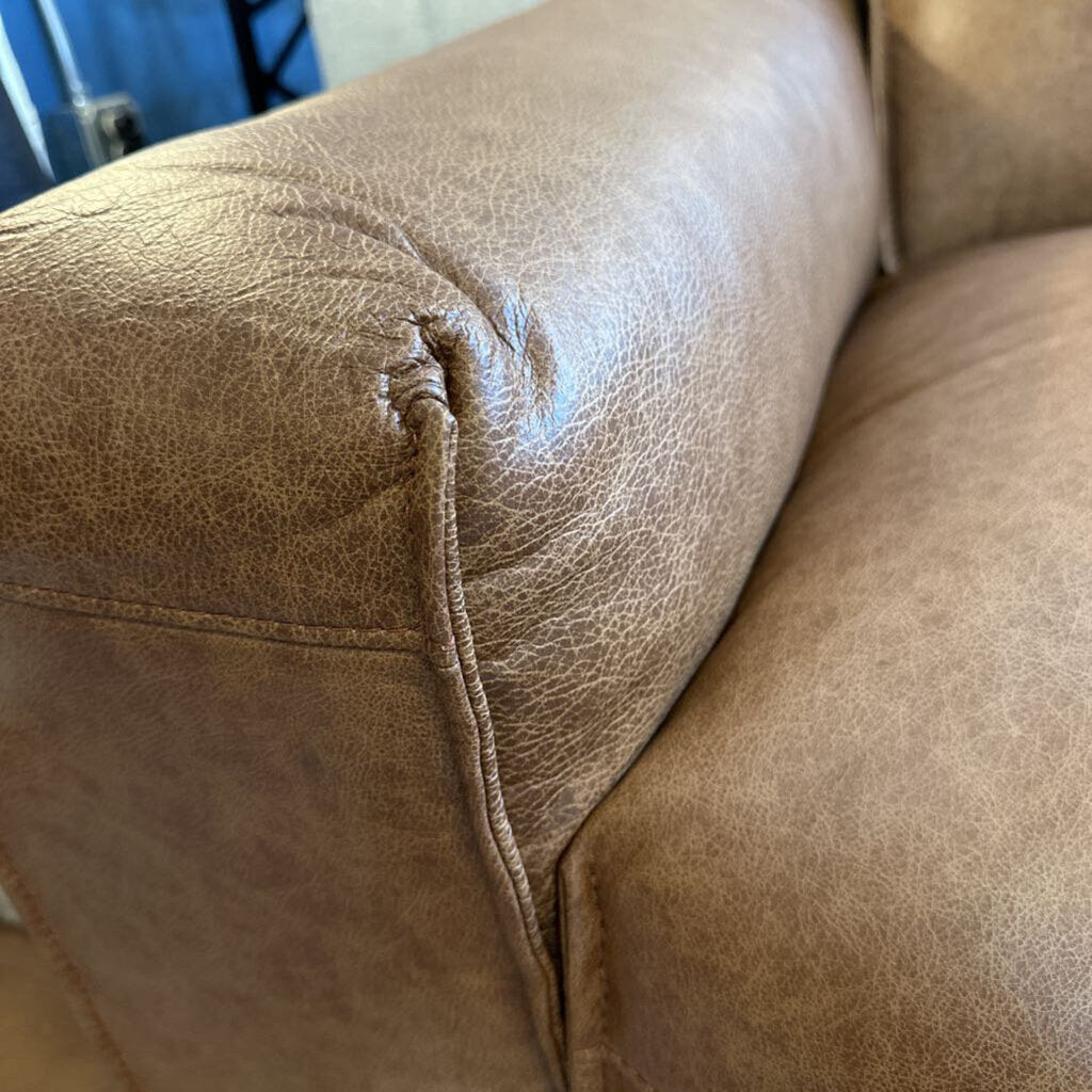 Brown leather sofa with a visible tear in the fabric.