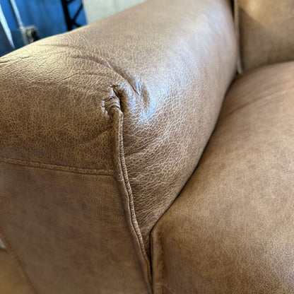 Brown leather sofa with a visible tear in the fabric.