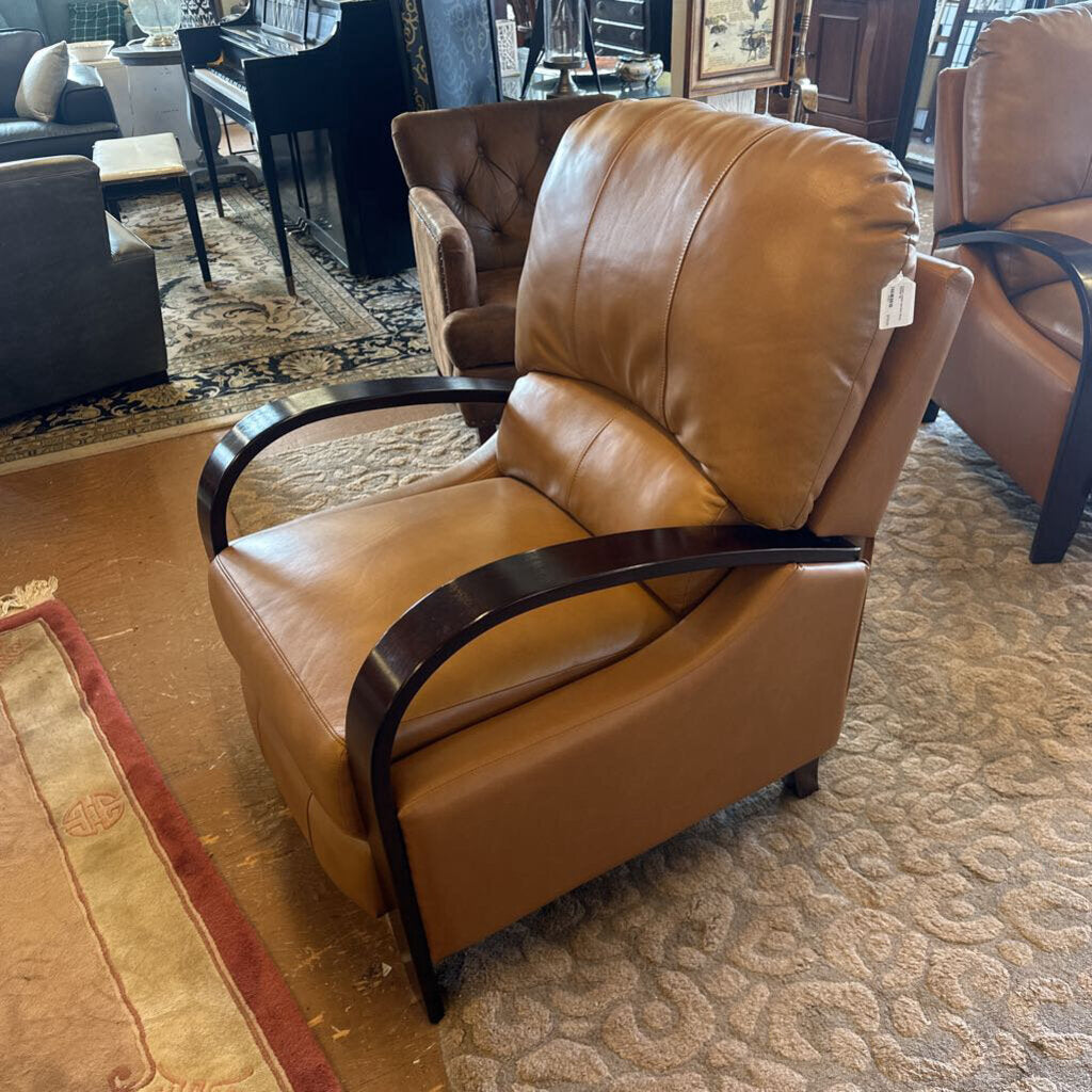 Brown leather armchair with wooden armrests in a showroom setting.