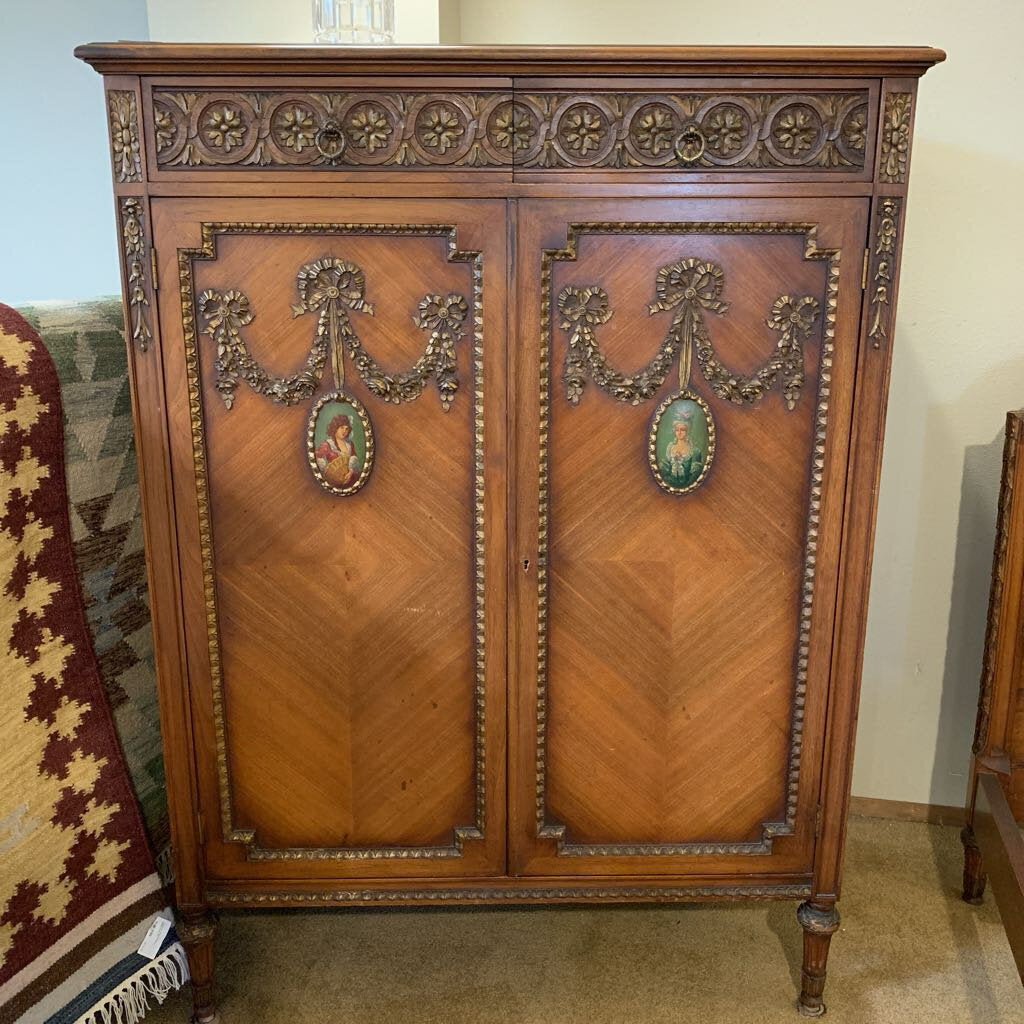Decorative wooden cabinet with intricate carvings and portraits in a room setting.