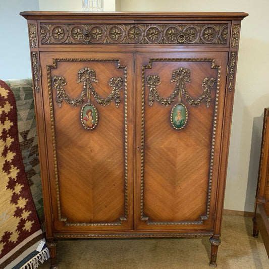Decorative wooden cabinet with intricate carvings and portraits in a room setting.