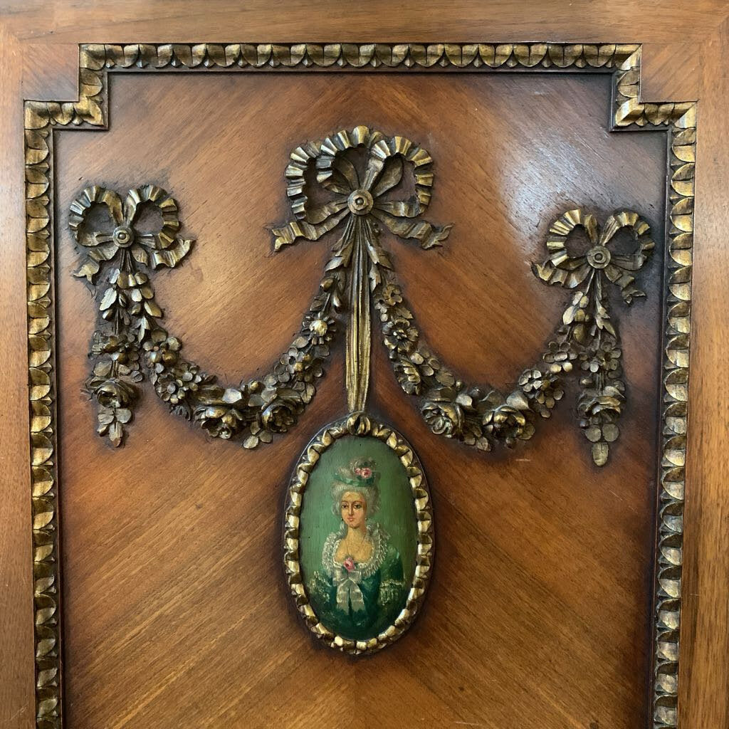 Decorative wooden panel with a gold ribbon and portrait in a wooden frame.