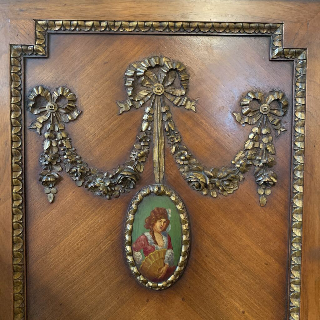 Decorative wooden panel with gold leaf and a small portrait inside a frame.