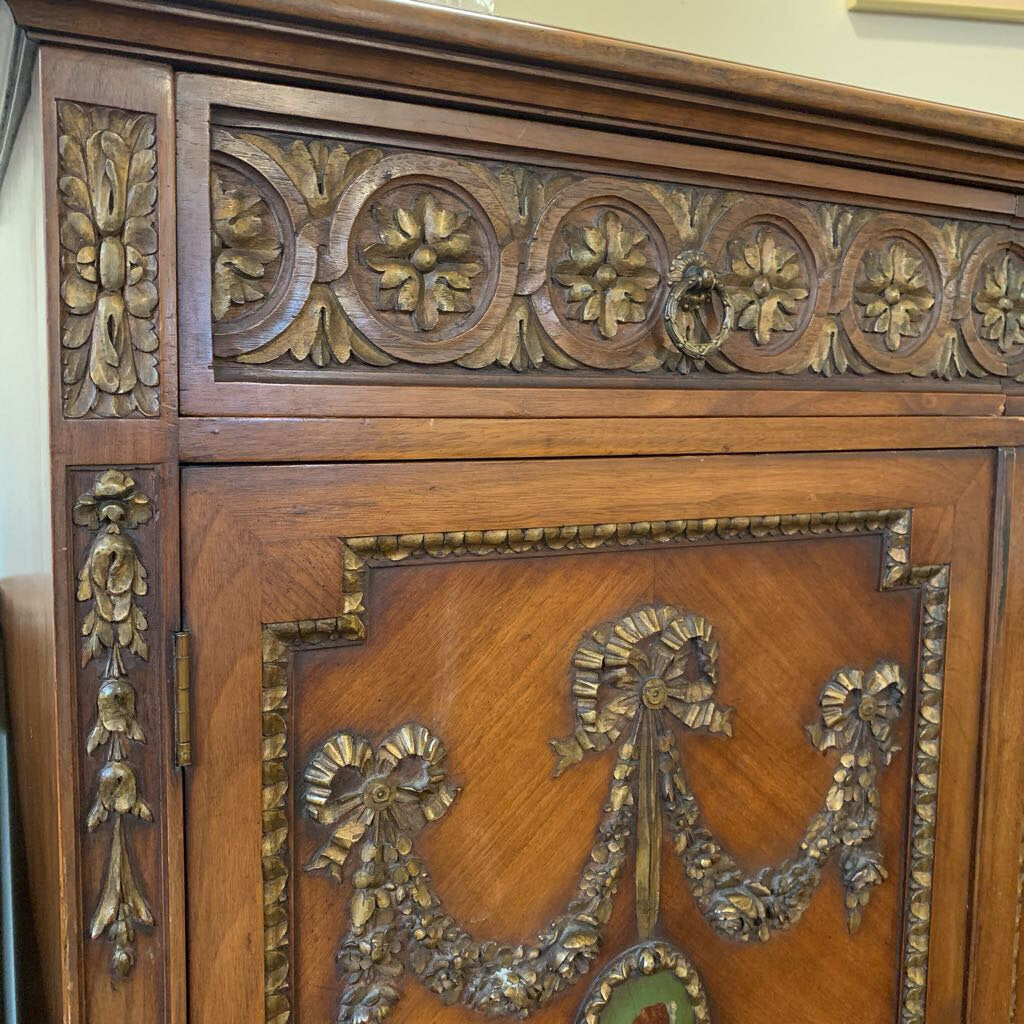 Close-up of an ornate wooden cabinet with intricate carvings and gold accents.
