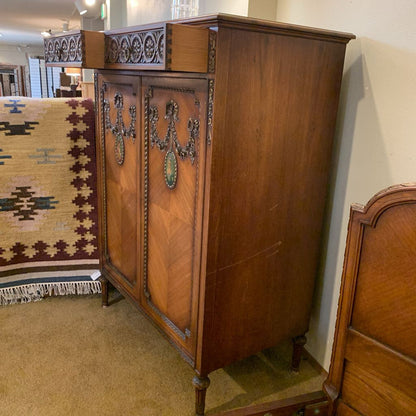 Vintage wooden cabinet with intricate carvings in a room setting.