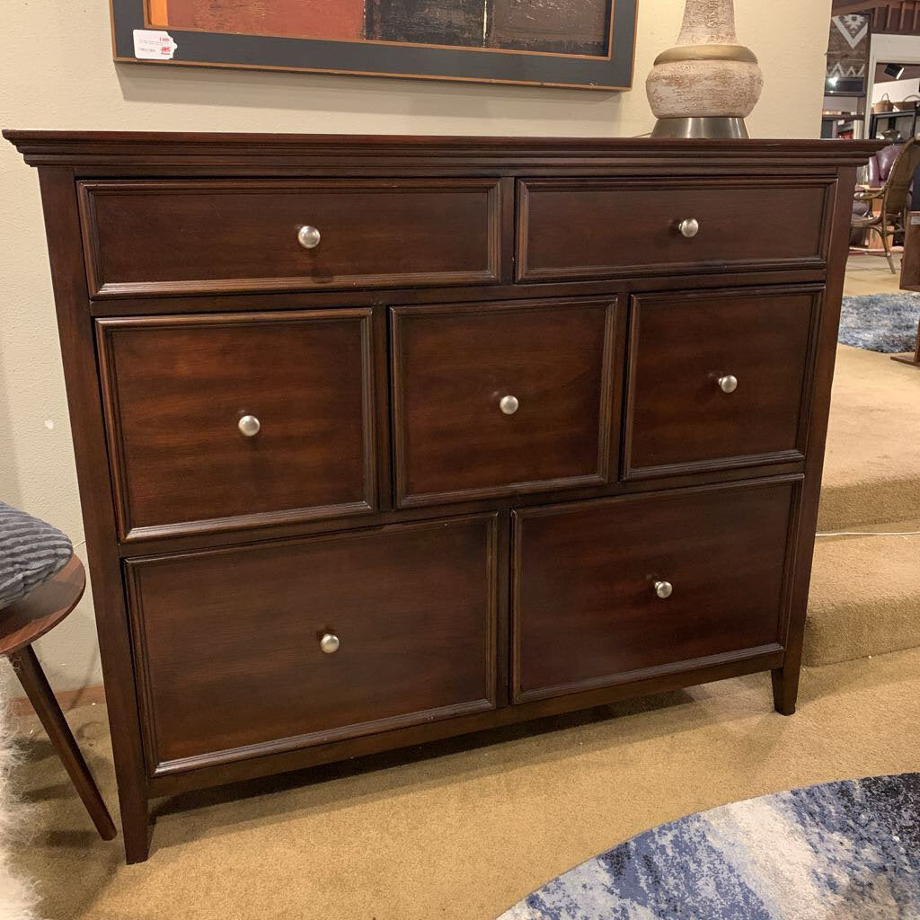 Dark wood dresser with multiple drawers in a room setting