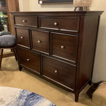 Dark wood dresser with multiple drawers in a room setting.