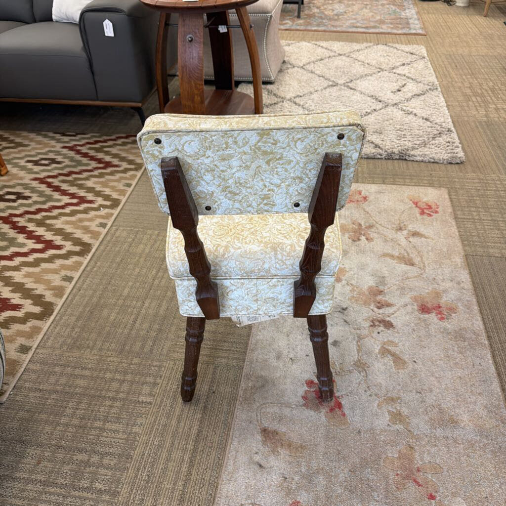 Vintage chair with floral patterned seat and wooden frame on a carpeted floor.