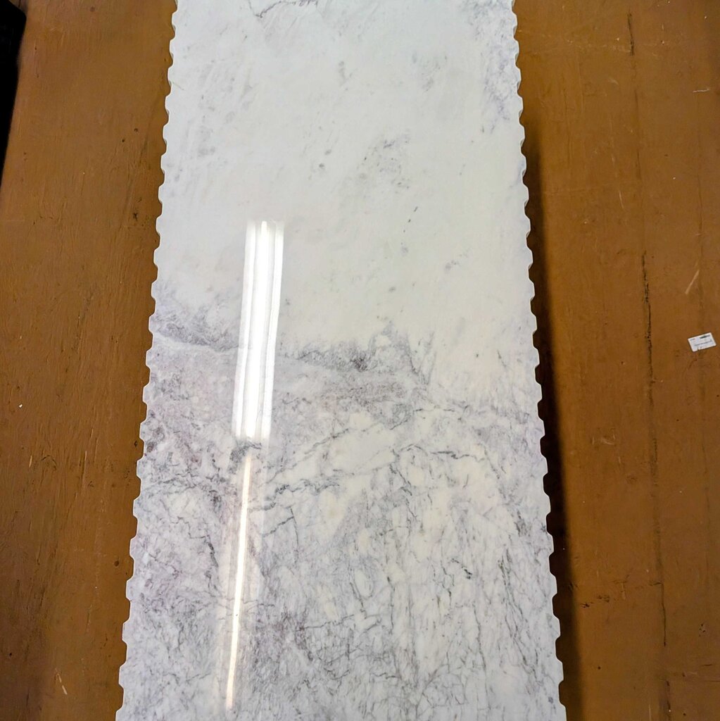 Long rectangular marble slab with a silver tool on a wooden surface
