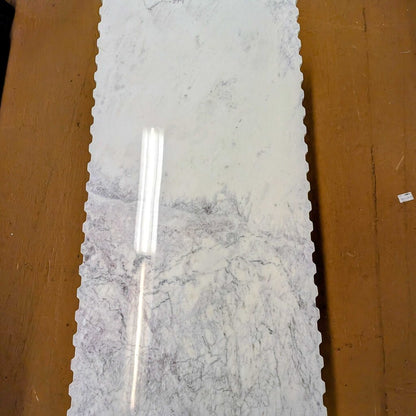 Long rectangular marble slab with a silver tool on a wooden surface
